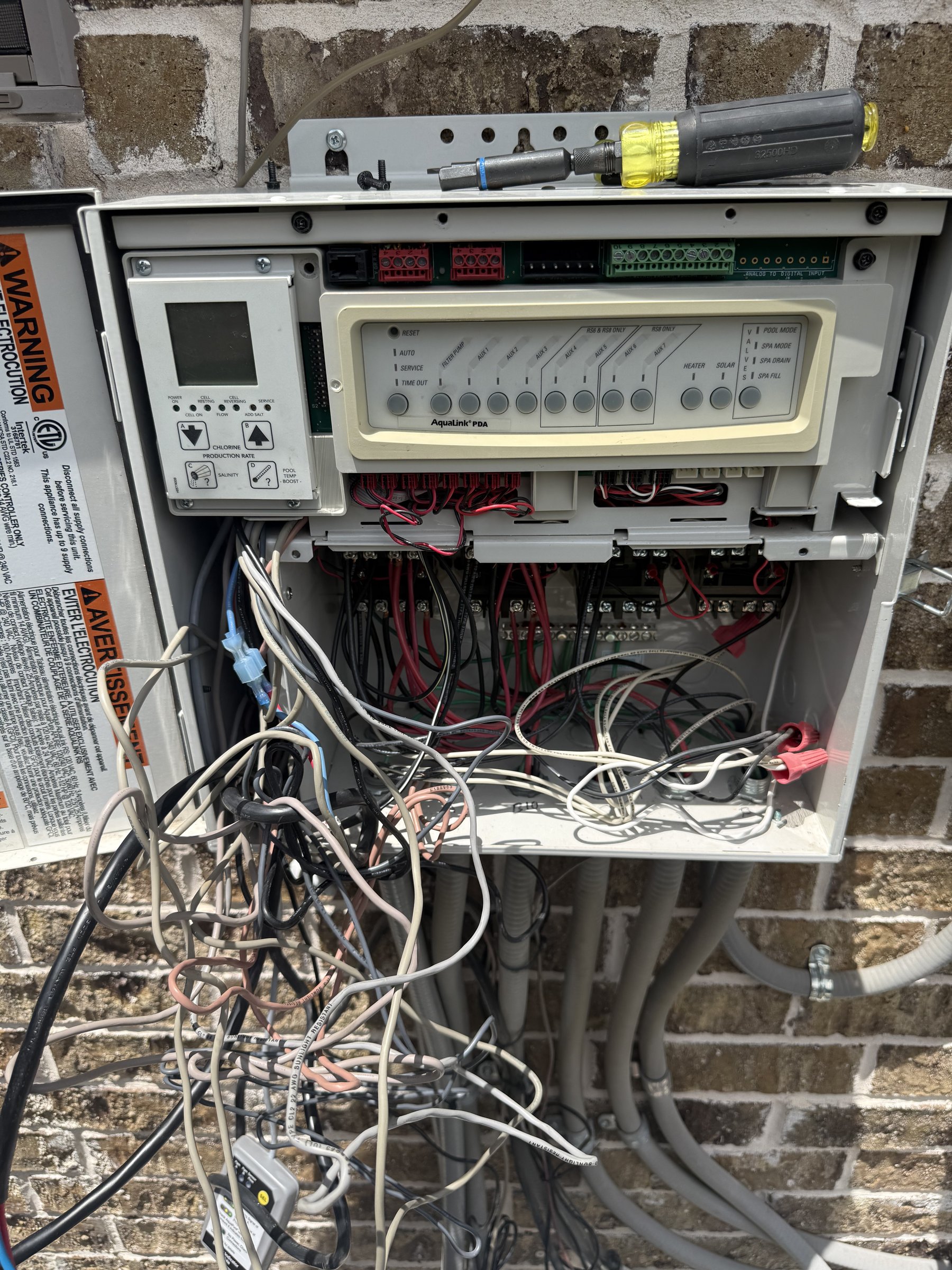 Technician servicing a pool automation control panel and wiring during equipment repair