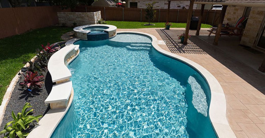 Backyard pool with raised spa and quartz finish completed by The Texas Pool Company