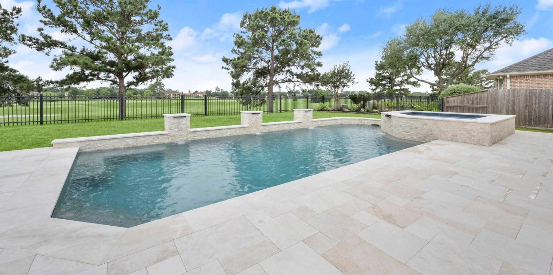 Remodeled backyard pool and raised spa with stone coping and travertine decking